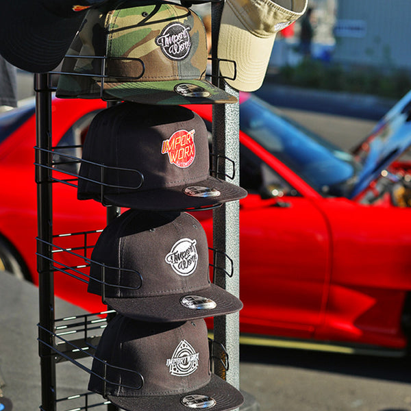 Collection of hats on a display rack with a car in the background